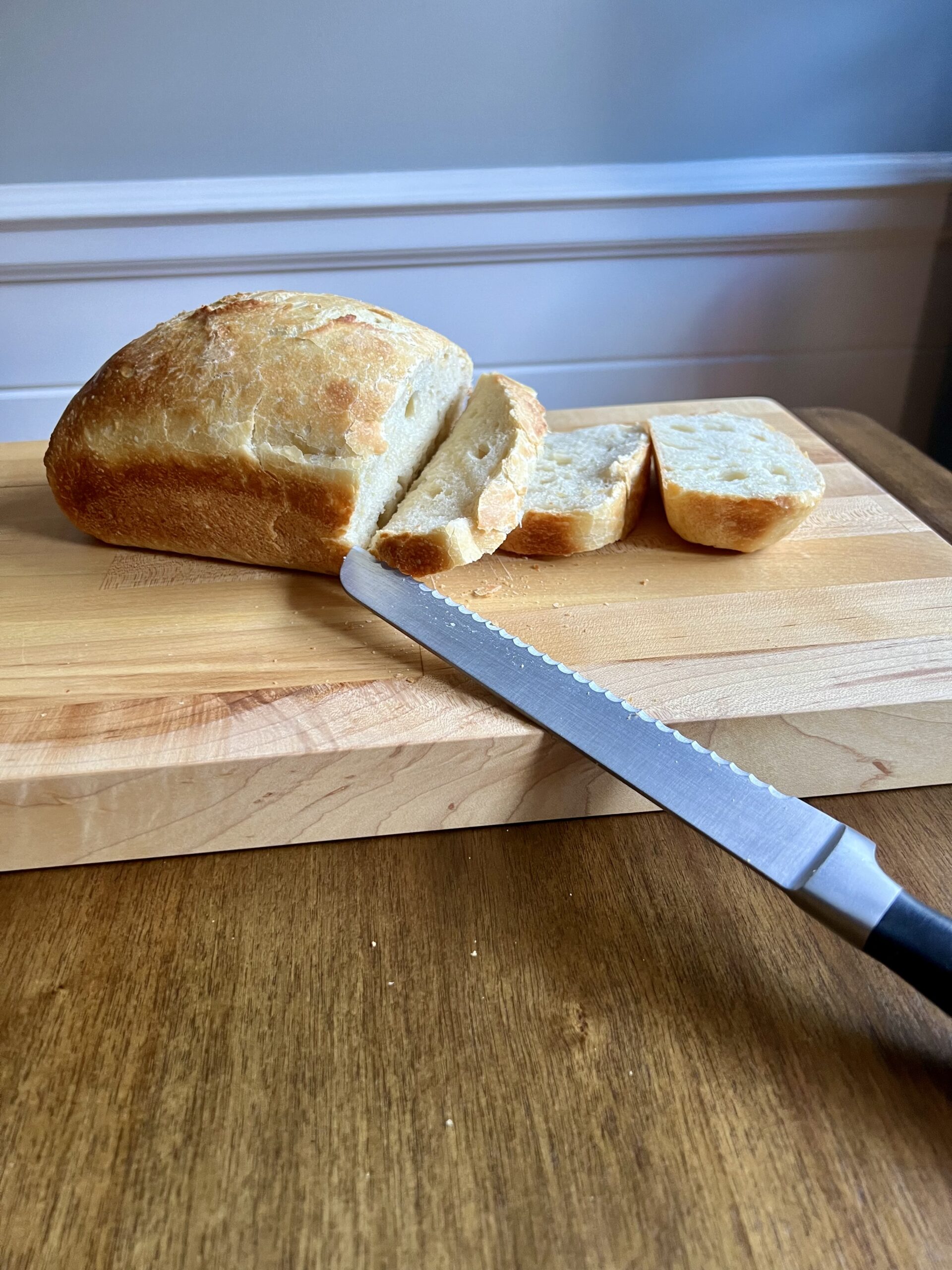 Single loaf of homemade sourdough sandwich bread sitting on a wooden cutting board