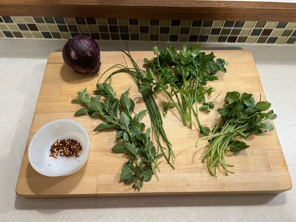 Fresh herbs sitting on a wooden cutting board. 