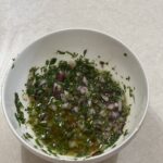 Fresh herb sauce in a white bowl on a white countertop