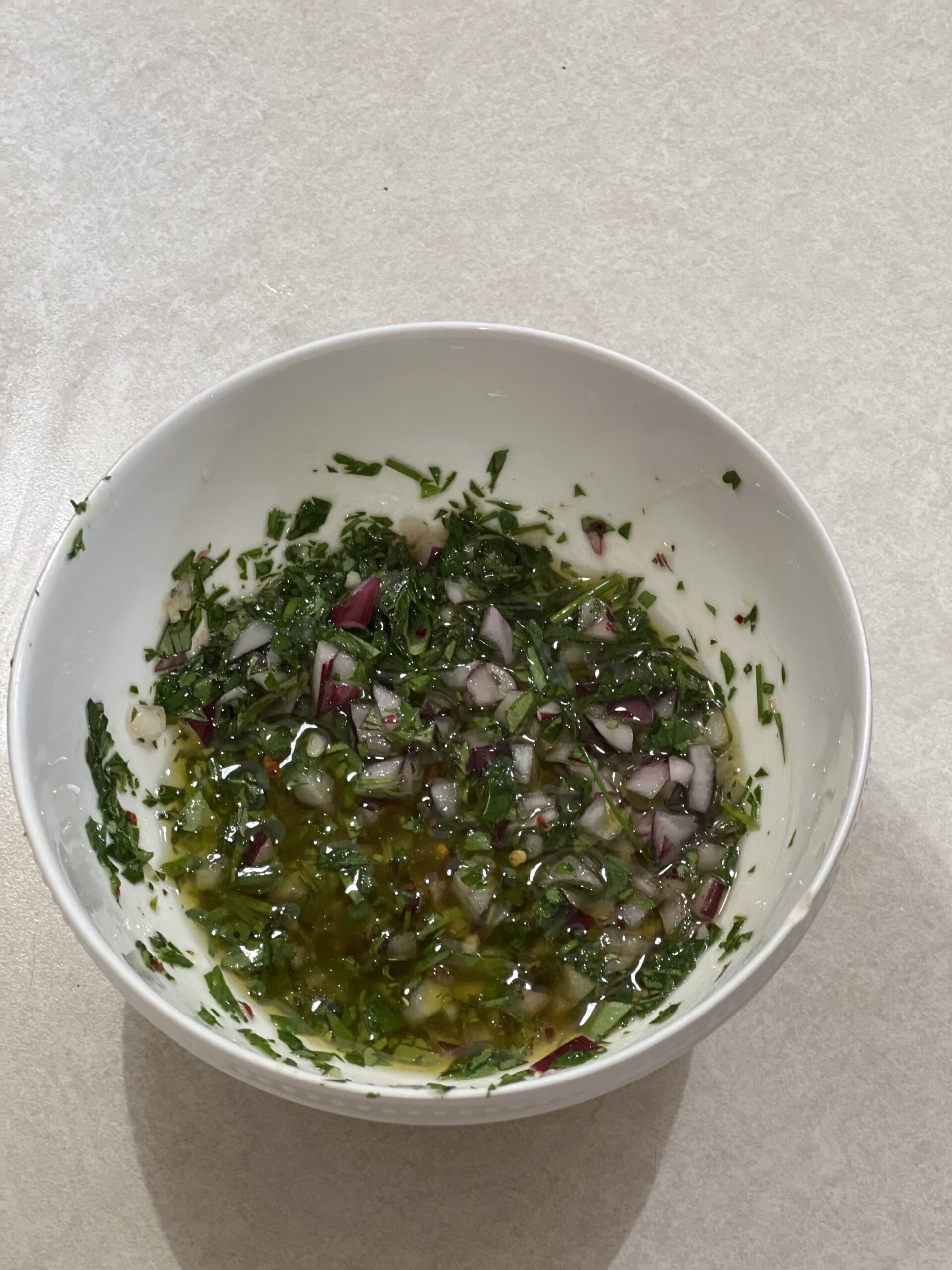 Fresh herb sauce in a white bowl on a white countertop