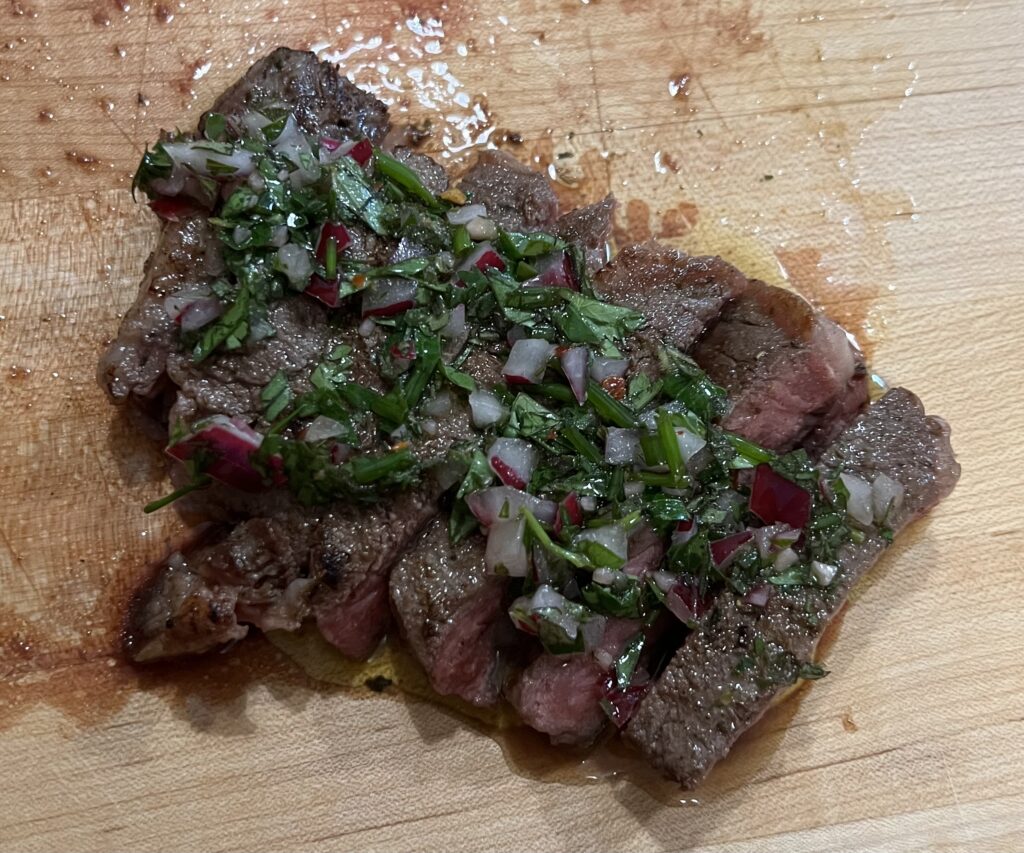 Chimichurri sauce on top of cut steak.