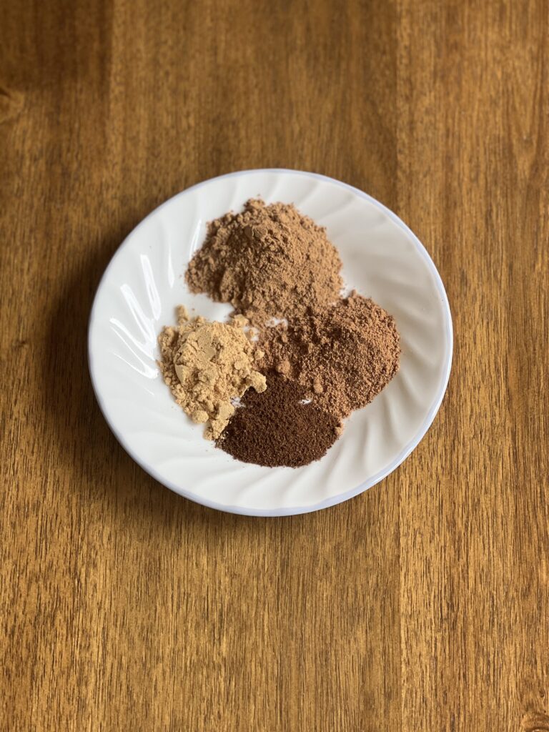 cinnamon, nutmeg, ginger, clove, and all spice on a white plate. 