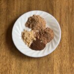 cinnamon, nutmeg, clove, ginger and allspice spices together on a plate.