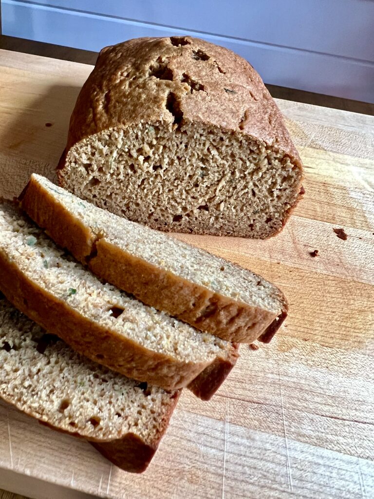 Sliced pumpkin zucchini bread sitting on a wooden cutting board