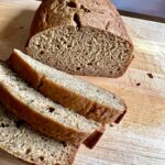 A sliced loaf of pumpkin zucchini bread resting on a wooden cutting board