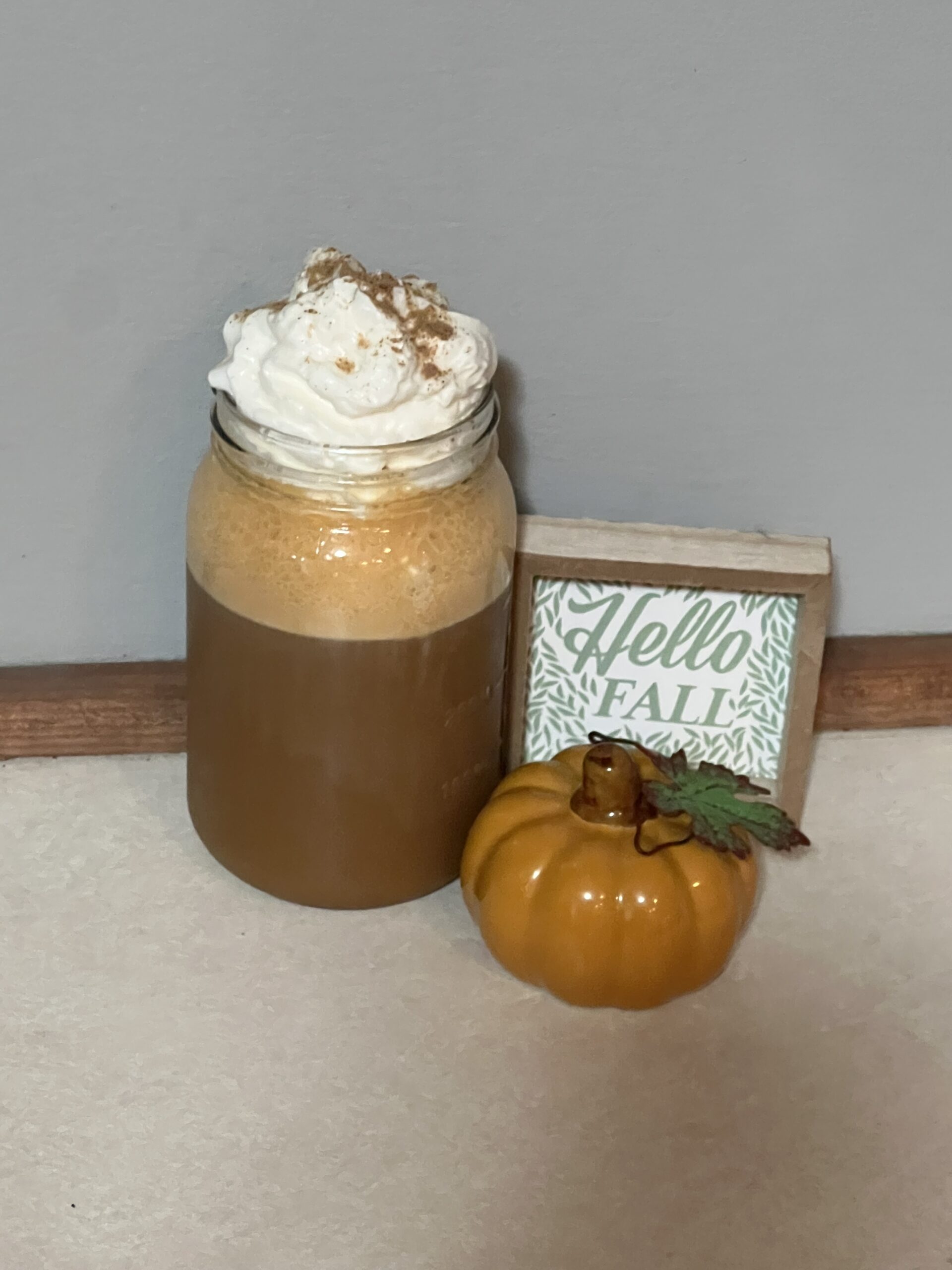 Iced pumpkin spice latte siting on the counter next to a pumpkin