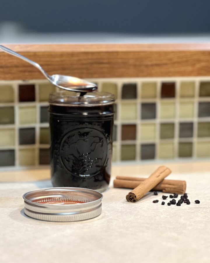 The best homemade elderberry syrup with spoon sitting on the counter