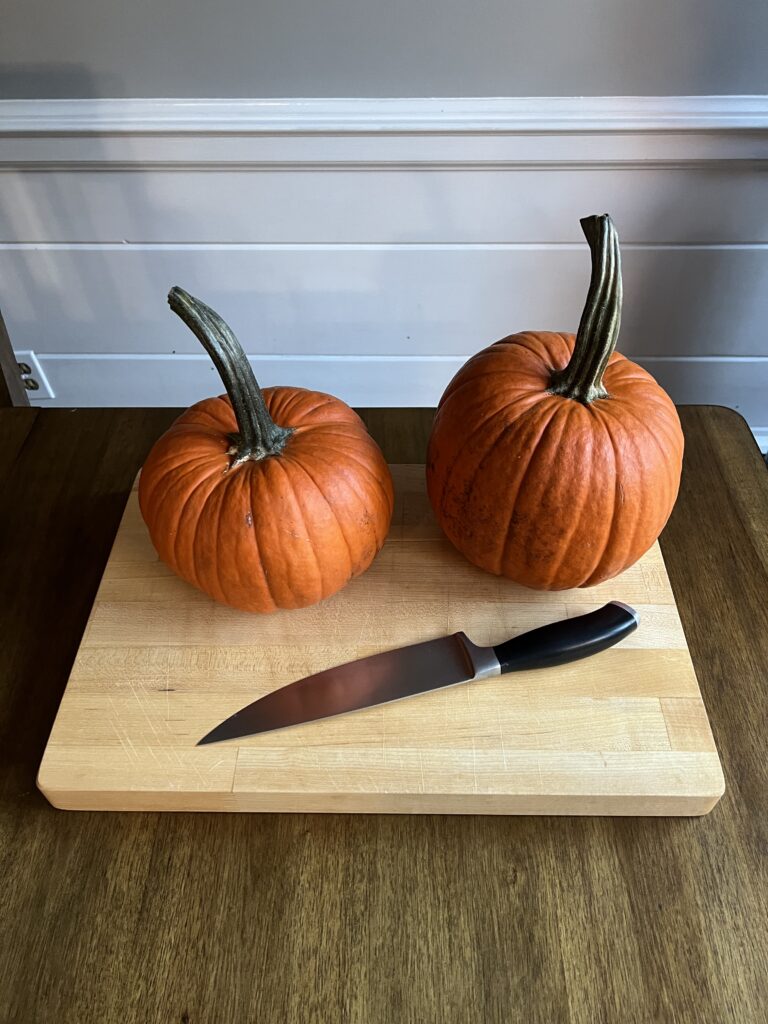 How to roast a pumpkin two pumpkins resting on wooden cutting board